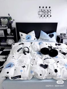 an unmade bed with black and white decorations on the comforter, pillows and headphones