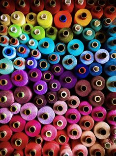 many spools of thread are stacked on top of each other in different colors