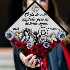 a woman holding a graduation cap decorated with flowers and writing on the front, in spanish