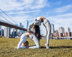 two women doing yoga in front of the brooklyn bridge