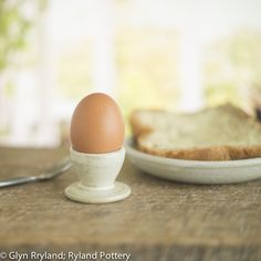 an egg sitting on top of a plate next to bread