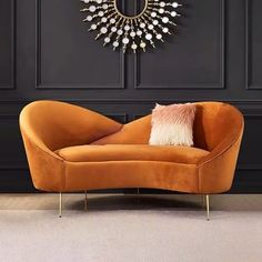 an orange chair with a pillow on it in front of a black wall and a wreath