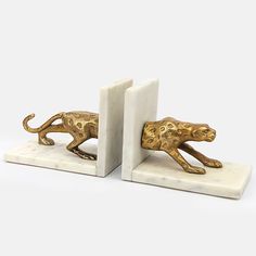 two marble bookends with gold painted leopard figurines on white marble bases