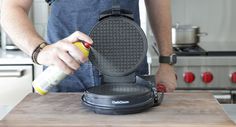 a man in an apron is using a waffle iron