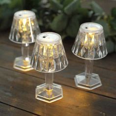 three clear glass lamps sitting on top of a wooden table