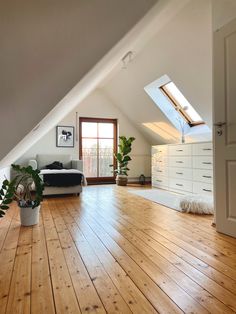 an attic bedroom with hardwood floors and white furniture