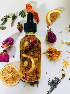 a bottle filled with liquid surrounded by dried flowers and orange slices on a white surface