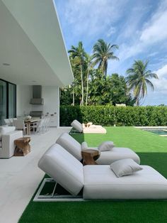 a white couch sitting on top of a lush green field next to a swimming pool