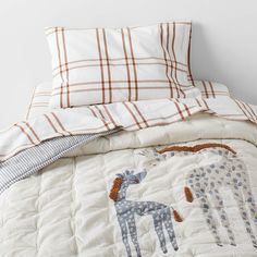 an unmade bed with two giraffes on the comforter and pillows