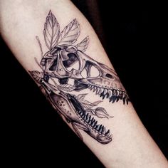 a black and white photo of a dinosaur skull with leaves on it's head