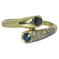 This 18K Yellow Gold Ring with Ruby, Blue Sapphire, and 0.18 ct Brilliant-Cut Diamonds is a stunning example of vintage European craftsmanship. Crafted from luxurious 18-carat yellow gold, this pre-loved ring features a vibrant ruby and a striking blue sapphire, elegantly complemented by brilliant-cut diamonds on one shoulder. With its refined and timeless design, this ring is perfect for those who appreciate sophisticated and elegant jewelry. Whether worn daily or for special occasions, this vi Gold Ring With Ruby, Ring With Ruby, Yellow Gold Solitaire Ring, Yellow Gold Cocktail Ring, Brilliant Cut Diamond Ring, Gold Solitaire Ring, Vintage European, White Gold Set, Gold Cocktail Ring