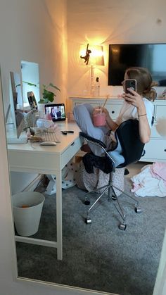 a woman sitting at a desk with a baby in her lap taking a selfie