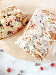 a loaf of cranberry bread with icing on a cutting board next to another loaf