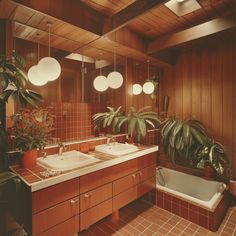 a bathroom with two sinks and plants in the bathtub, along with three hanging lights