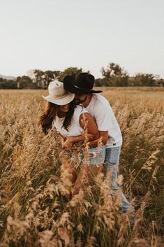 two people standing in tall grass with one holding the other's head and hugging