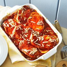 a casserole dish with meat and cheese on top, next to a fork