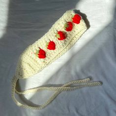 a white crocheted bag with red tomatoes on the front and bottom, attached to a string