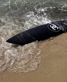 a surfboard is laying on the sand at the beach with waves coming in to shore