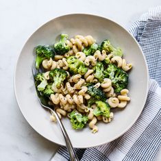 a white bowl filled with pasta and broccoli on top of a blue towel