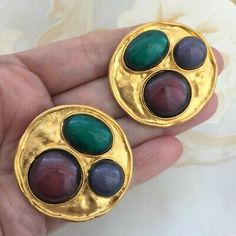 pair of gold tone earrings with green, red and purple stones in the middle of each ear