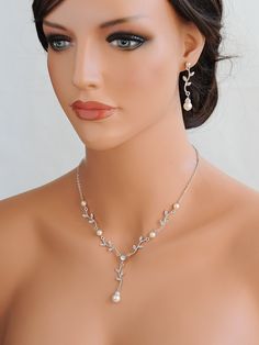 a mannequin head wearing a necklace and earrings with pearls on it's neck