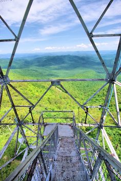 a view from the top of a metal structure looking down at green hills and trees