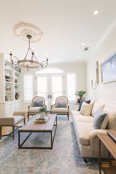 a living room filled with furniture and a chandelier hanging over the top of it