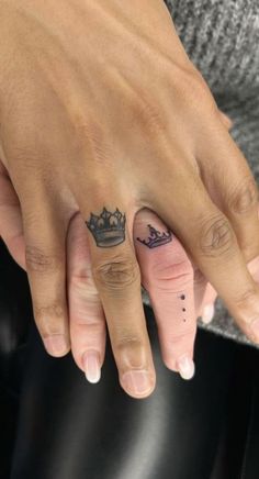 two people with tattoos on their fingers and one has a crown tattooed on the finger