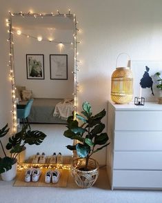 a bedroom with lights and plants on the floor in front of a mirror that is lit up