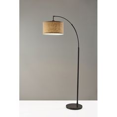 a floor lamp with a fabric shade on the base and a black metal pole, against a gray background