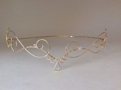 a gold tiara with swirls and pearls on the headband is shown against a white background