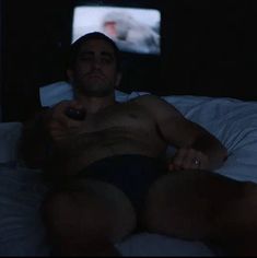 a man laying in bed holding a remote control