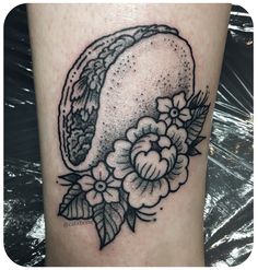 a black and white photo of a tattoo on the leg, with flowers around it