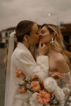 two women in wedding dresses kissing each other