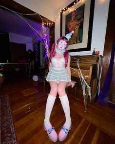 a woman with pink hair and blue makeup is posing for the camera in her costume