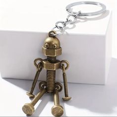 a metal robot keychain sitting on top of a white box