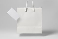 a white shopping bag with a blank note attached to the handle, on a gray background