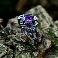 a ring with an amethorate stone in the center on top of rocks