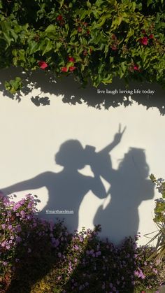 the shadow of two people standing next to each other in front of a white wall