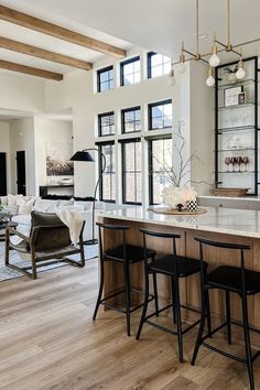 a large open concept kitchen and living room with wood flooring, white walls and windows