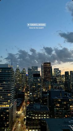 the city skyline is lit up at night, with clouds in the sky above it