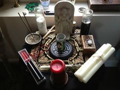 an altar with candles, incenses and other items on it in front of a window