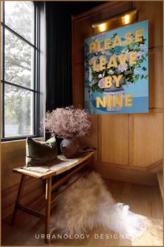 a wooden bench sitting in front of a window next to a vase filled with flowers