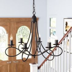 a chandelier hanging from the ceiling in a room with wooden stairs and windows