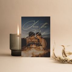 a candle next to a card with the words save the date on it and an image of two people holding each other