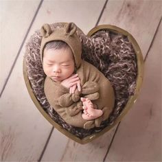 a newborn baby is sleeping in a heart shaped box with a teddy bear on it