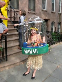 a woman wearing a hula skirt and headdress standing in front of stairs