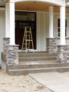 a house with steps leading up to the front door, and a ladder on the porch