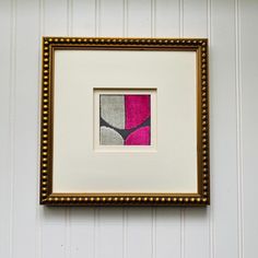 a framed art piece hanging on the wall next to a white and yellow striped wall