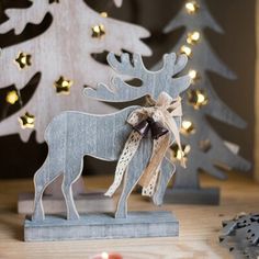 a wooden moose with a bow on it's neck standing in front of a christmas tree